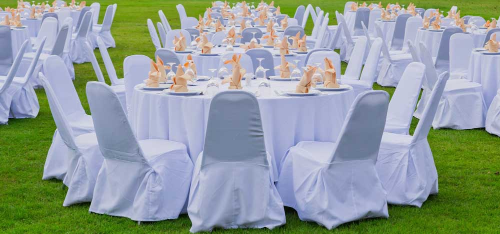 round tables, place settings and chairs set up outside for a wedding